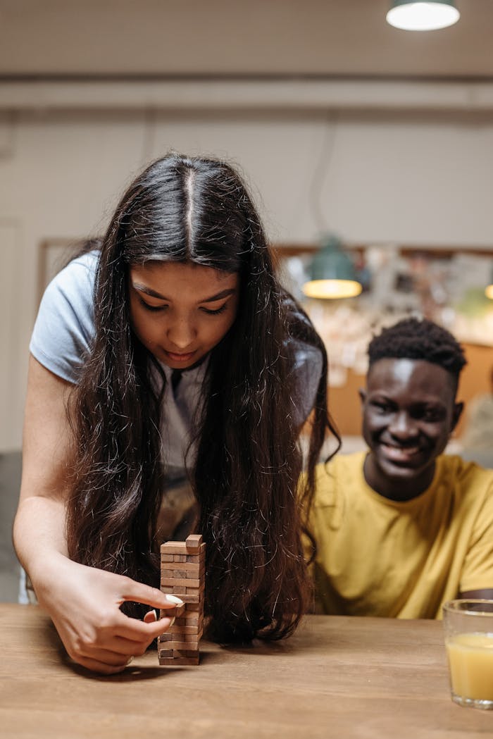 Two friends playing Jenga indoors, showcasing fun and togetherness.